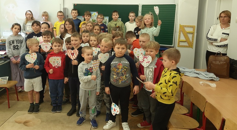 Dzieci stoją na środku sali i prezentują wiosenne serca.jpg
