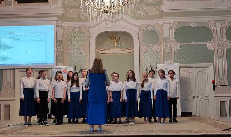 Chór i dyrygent stoją na scenie.jpg