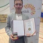 uczeń  trzyma w rekach certyfikat i medal.jpg