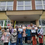 Grupa dzieci stoi przed budynkiem Młodzieżowego Domu Kultury pokazując swoje prace wykonane na zajęciach..jpg