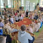 Uczniowie wraz z przedszkolakami siedzą na dywanie
