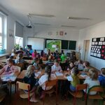 Uczniowie wraz z przedszkolakami siedzą w ławkach
