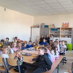 Dzieci siedzą w ławkach podczas zajęć