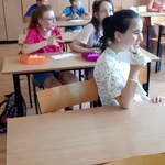 uczniowie siedzą w ławkach, jedzą ciasto