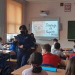 pani policjantka z uczniami siedzącymi w ławkach szkolnych
