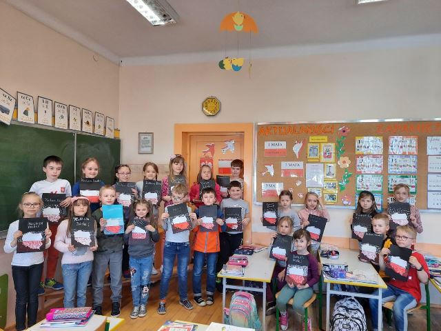 uczniowie trzymają w rękach swoje prace