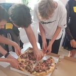 uczniowie dzielą się pizzą