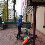 chłopiec  trzyma miotłę przed budynkiem