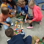 grupa uczniów buduje zamek z drewnianych klocków