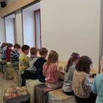 Uczniowie siedzą i wyklejają  medale plasteliną