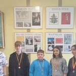 3 chłopców, dziewczynka i nauczycielka stoją z medalami na szyji