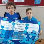 dwóch chłopców i nauczyciel trzyma plakat z w niebieskie serduszka z pozdrowieniami.jpg