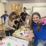 Uśmiechniete dzieci z pomalowanymi dłońmi robią plakat o prawach dziecka.jpg