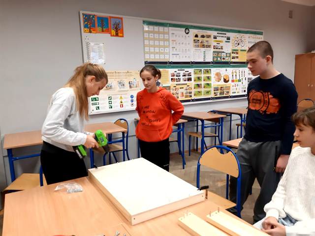 uczennica trzyma wkrętarkę, razem z innymi uczniami składa szafkę.jpg