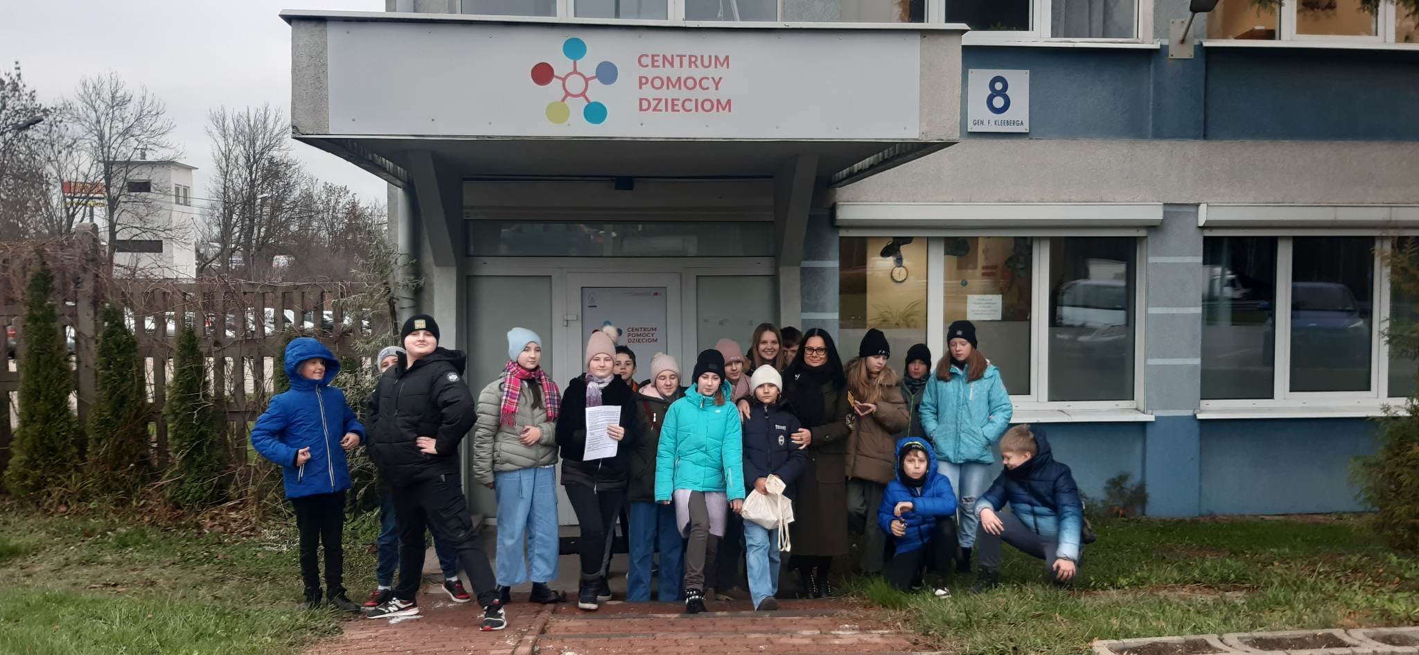 grupa dzieci stoi przed budynkiem z napisem Centrum Pomocy Dzieciom .jpg