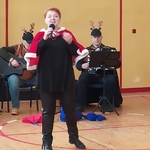 Kobieta z czerwoną, świąteczną peleryną śpiewa kolędę.jpg
