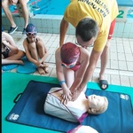 ratownik pokazujący uczniom zasady pierwszej pomocy na basenie.jpg