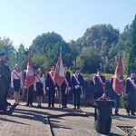 dziewczynki i chłopak stoją ze sztandarem w miejscu składania kwiatów.jpg